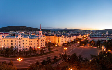 Obraz premium Aerial view of the city of Magadan. Top view of the streets and buildings. A beautiful tower with a spire. Historic city center. Lenin Avenue, Magadan, Far East of Russia. Morning twilight.