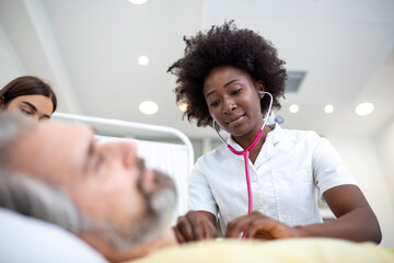 Senior patient on bed talking to African American female doctor in hospital room, Health care and insurance concept. Doctor comforting elderly patient in hospital bed or counsel diagnosis health.