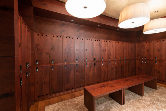 Interior of a locker room. Clean empty dressing room with big lockers with wooden door and wooden bench