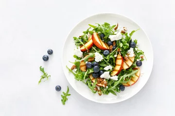 Zelfklevend Fotobehang Peach, blueberry and arugula fresh fruit salad with cheese and almond nuts, top view © Sea Wave