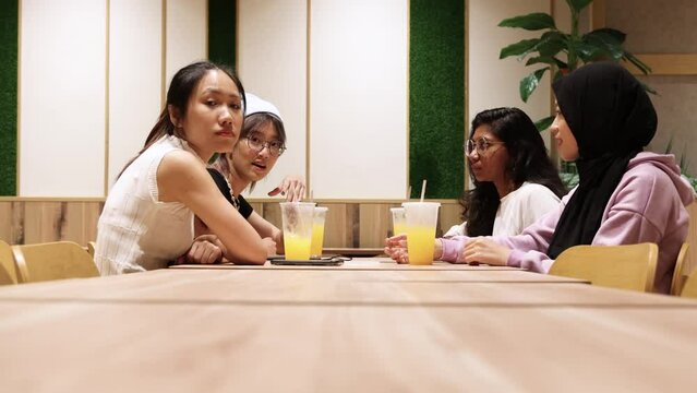 young attractive Asian group woman friends colleagues students indoor dining café restaurant area talk drink discuss laugh happy table chair bench