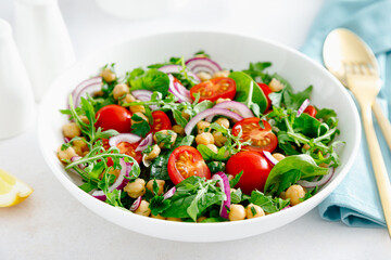 Vegetarian chickpea salad with tomatoes, arugula, parsley, spinach and red onion. Healthy food, diet