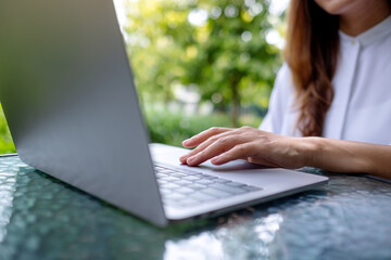 Closeup image of a businesswoman working and typing on laptop computer keyboard in the outdoors