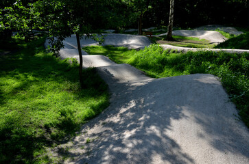 forest in which there is a track for bicycles trail tilted bends one after the other dug in the ground into perfect shapes mountain bikes even for children, glade, sun, shadows, racing  new, lawn
