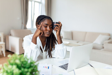 Exhausted businesswoman having a headache in home office. African American creative woman working...