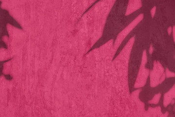 Shadow of leaves on pink concrete wall texture with roughness and irregularities. Abstract trendy...