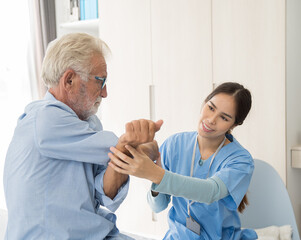 Woman nurse physical therapy senior man at hospital ward. Asian female nurse caring elderly man...