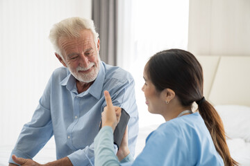 Fototapeta premium Woman nurse measure the pressure senior man at hospital ward. Asian female nurse caring elderly man patient in room at nursing home. Hospital care and older adults concept