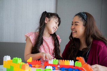 Asian family mother and little asian girl smiling playing with toy build blocks at home. 