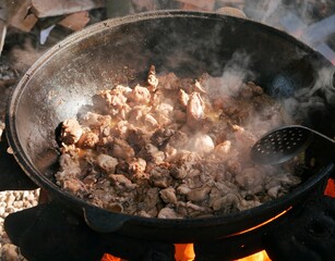 Cooking in a cauldron on open air on a summer day. Roasting meat in kazan over a fire....