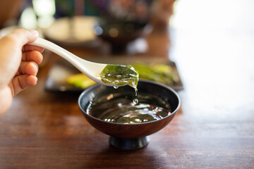 Hand with spoon eating traditional seaweed Japanese soup. © bignai