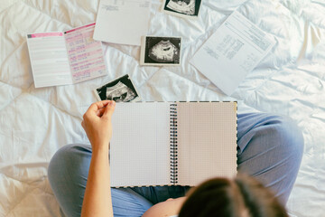 Pregnancy list woman writing. Beautiful pregnant woman writing check list. Happy pregnancy lady holding notepad. Concept maternity, childbirth.
