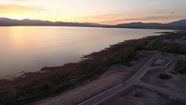Aerial view of sunset over construction area for new homes next to lake with waterfront property in Utah.