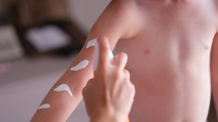 Mother applying sunscreen to baby skin closeup