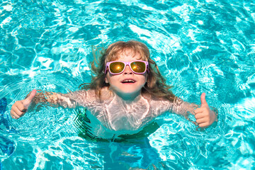 Fototapeta premium Child water toys. Children play in tropical resort. Happy child playing in swimming pool. Summer kids vacation.