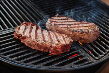 Barbecue dry aged wagyu roast beef steak grilled as close-up on a charcoal grill with fire and smoke