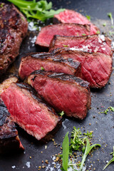 Barbecue dry aged wagyu roast beef steak with lettuce and spice served as close-up on a rustic black board