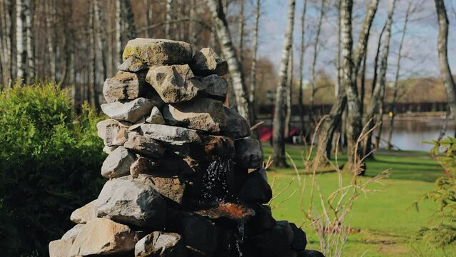 Water flows down a small pyramid of stones. Beautiful composition in the park