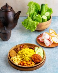 Indonesian yellow rice served with balado eggs, tempeh orek, vermicelli, potato fried chili sauce, where yellow rice is a typical breakfast menu for Southeast Asian people, especially Indonesia.