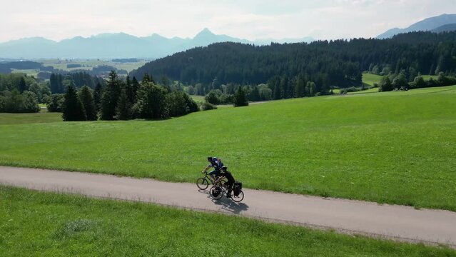 Two cyclists rolling downhill in a green mountain landscape