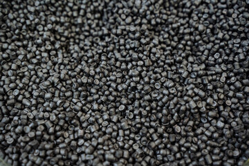Black plastic chips are shot close-up, granules of polymeric material for the chemical industry, the structure of raw materials in a pile of small plastic.