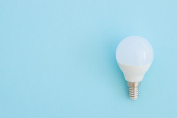 LED light bulb lies on a pastel blue background. Energy saving concept. Minimalism, top view