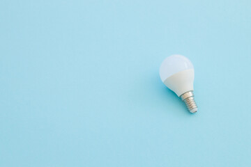 LED light bulb lies on a pastel blue background. Energy saving concept. Minimalism, top view