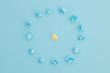 Top view of unique crumpled yellow paper among blue on blue background. New idea. Be unique