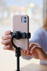 Close-up of a phone on a tripod filming a girl blogging