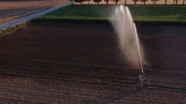 Aerial View of irrigation and Watering Machinery in the Middle of Agricultural Farmland Splashing Water Around on the Field Soil, Countryside of Cingoli, Italy