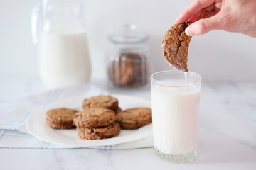 Woman's hand dipping homemade cookies into a glass of milk