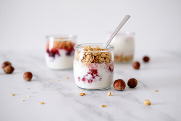 Oatmeal Granola with greek yogurt and nuts strawberry muesli in jars on light background