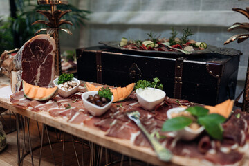 Serving and food exhibition of types of smoked meat and jerky with beautiful decor on stand closeup. Portion of meaty appetizer, nutritious dish. Food court, delicious meal, luxurious service