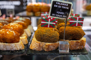 Typical snack in bars of Basque Country, pinchos or pinxtos, small fried croquette with squid and flag of Basque Country, San Sebastian, Spain
