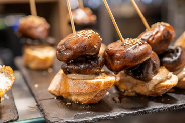 Typical snack is bars of Basque Country and Navarre, pinchos or pinxtos, small slices of bread upon which ingredient or mixture of ingredients is placed and fastened with skewers, San Sebastian, Spain