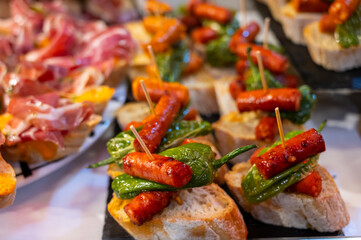 Typical snack of Basque Country and Navarre, pinchos or pinxtos, small piece of bread with different toppings, served in bar, Bilbao, Spain