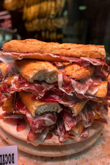 Spanish street food, fresh baked baguette bread with sliced iberian cured ham jamon, bocadillo