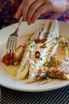 Eating in restaurant of fresh grilled on old charcoal parrillas sea bass fish in small fisherman's village Getaria, Basque Country, Spain