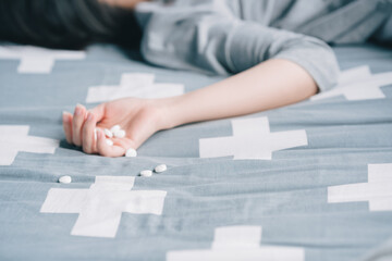 A woman takes sleeping pills to kill herself in bed.