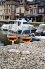Tasting of apple calvados drink in old Honfleur harbour with boats and old houses on background, Normandy, France