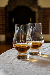 Two glasses of scotch whiskey with view on fireplace in old house on background, Edinburgh whisky tasting tour, Scotland