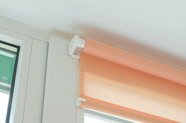 Fototapeta na wymiar Roller blinds on the window. Fastening roller blinds to the window frame with double-sided tape