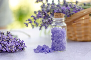Fototapeta na wymiar Lavender sea salt in a small transparent bottle and fresh lavender flowers. Lavender salt for spa treatments