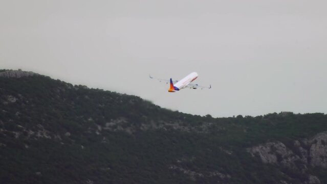 Airplane takeoff on a background of mountains. The plane rises into the sky in a beautiful landscape of mountain peaks.