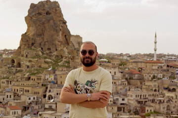 handsome man in sunglasses looking to the castle in cappadocia, turkey