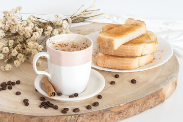 Glass cup with coffee and milk, cappuccino, served with toasted bread with butter on a light background. Simple and Portuguese breakfast.