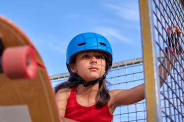 Girl skateboarder lifts her skateboard with her foot while being very concentrated before proceeding to perform a stunt.