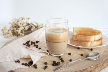 Glass cup with coffee and milk, cappuccino, served with toasted bread with butter on a light background. Simple and Portuguese breakfast.