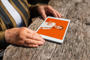 Obraz premium Happy elderly woman holding tablet pc computer looking at her granddaughter photo album at home.Technology,age,memories and people concept.Close up.