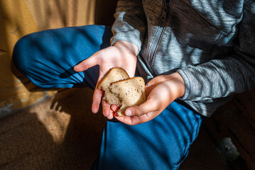 Poor Child homeless, beggar kid holds a pieces of black bread, war concept, poverty, crisis....